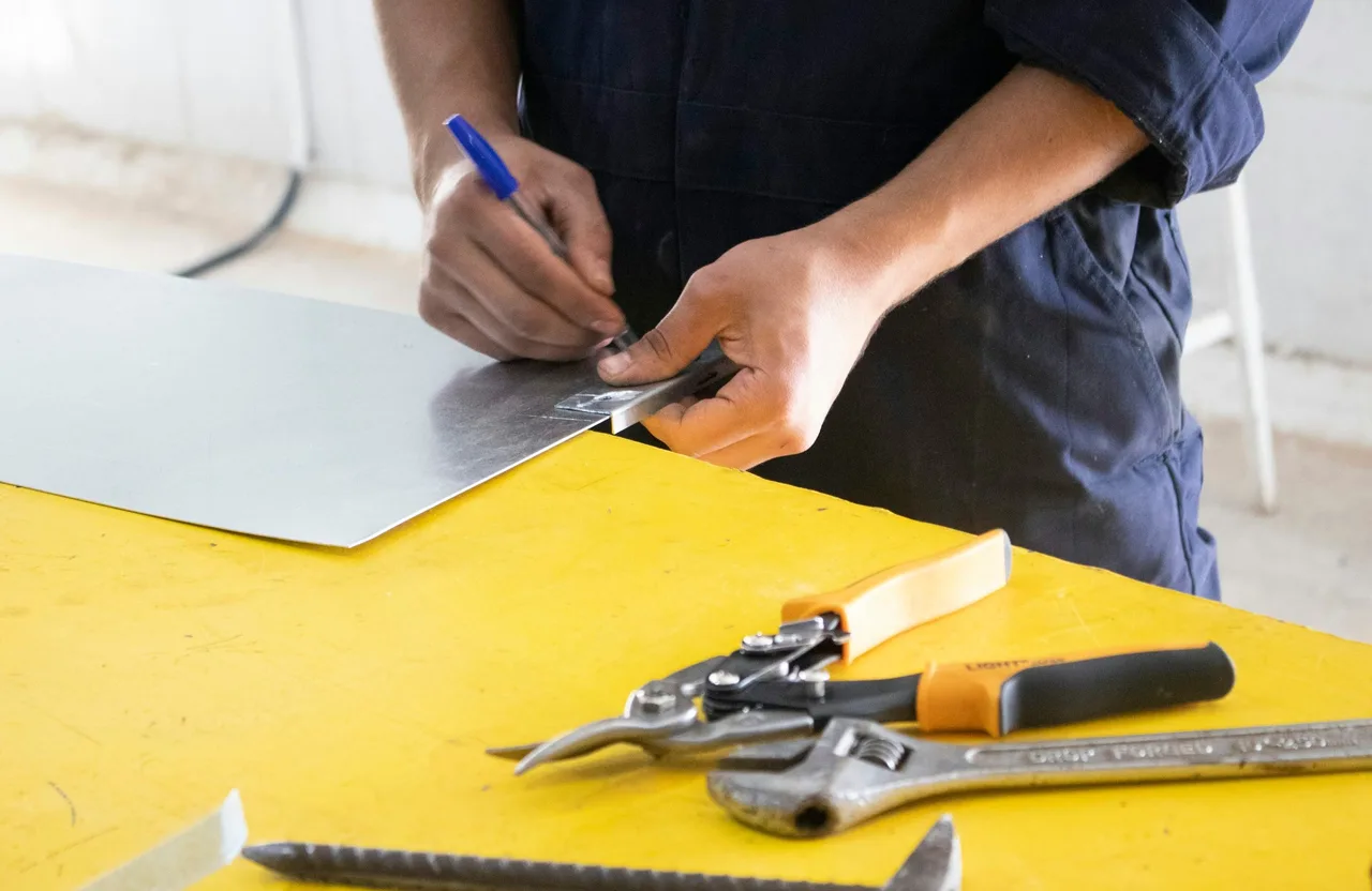 Handyman measuring sheet metal at a workbench — handyman CRM vs scheduling software comparison