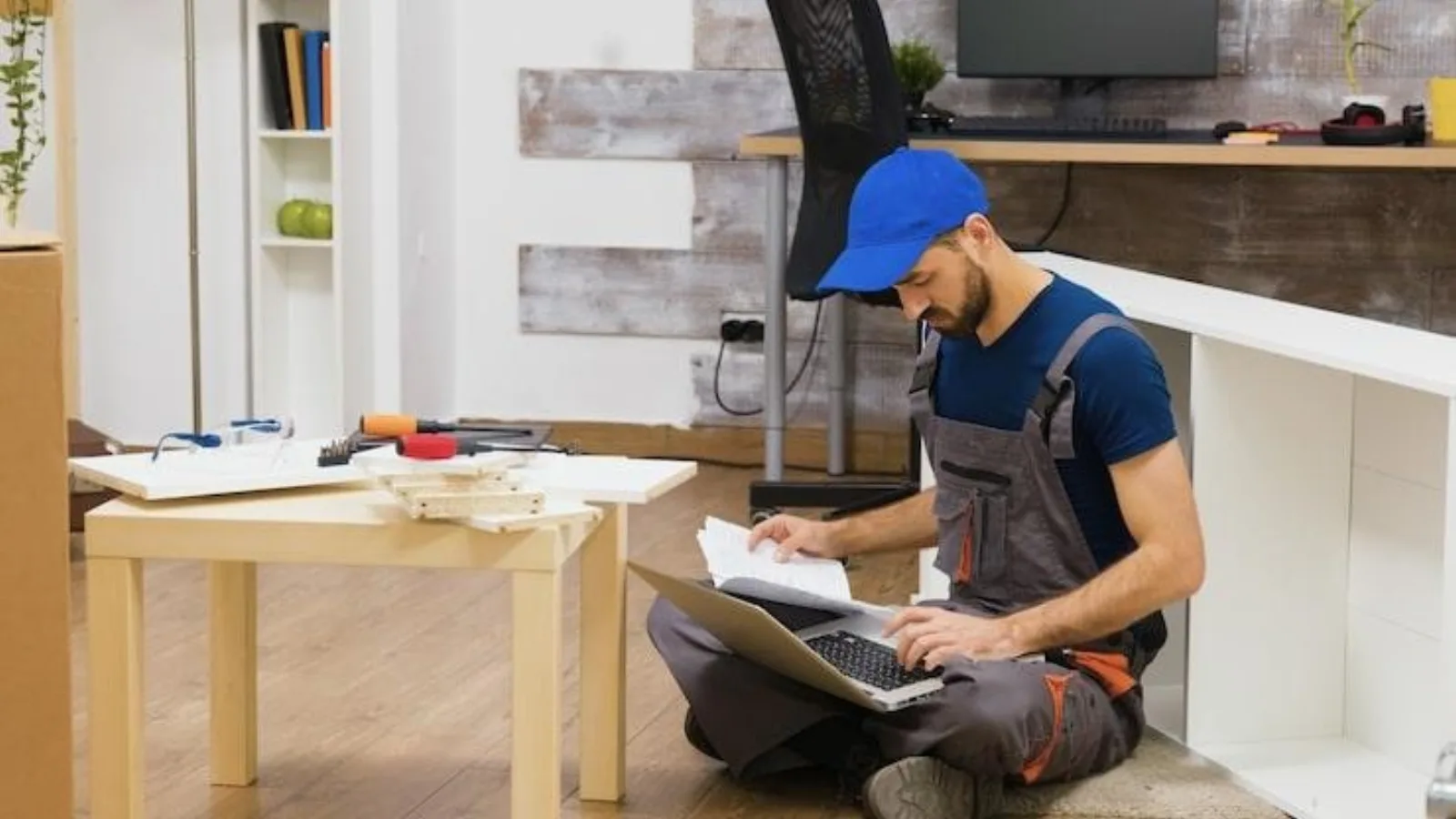 Tampa handyman using a laptop on the floor with tools nearby to manage bookings in the CRM